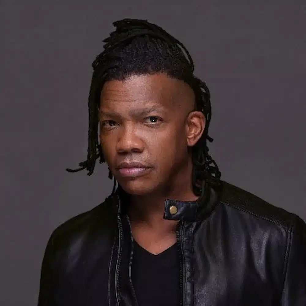 Micrófono en un escenario vacío con una cruz sombreada al fondo, simbolizando el impacto de las acusaciones contra Michael Tait en la música cristiana